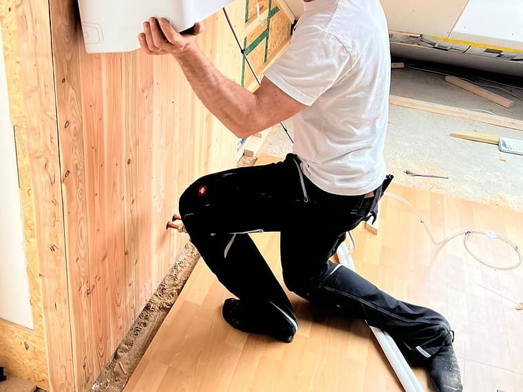 Montagearbeiten an einem Innengerät in einem holzverkleideten Wohnraum